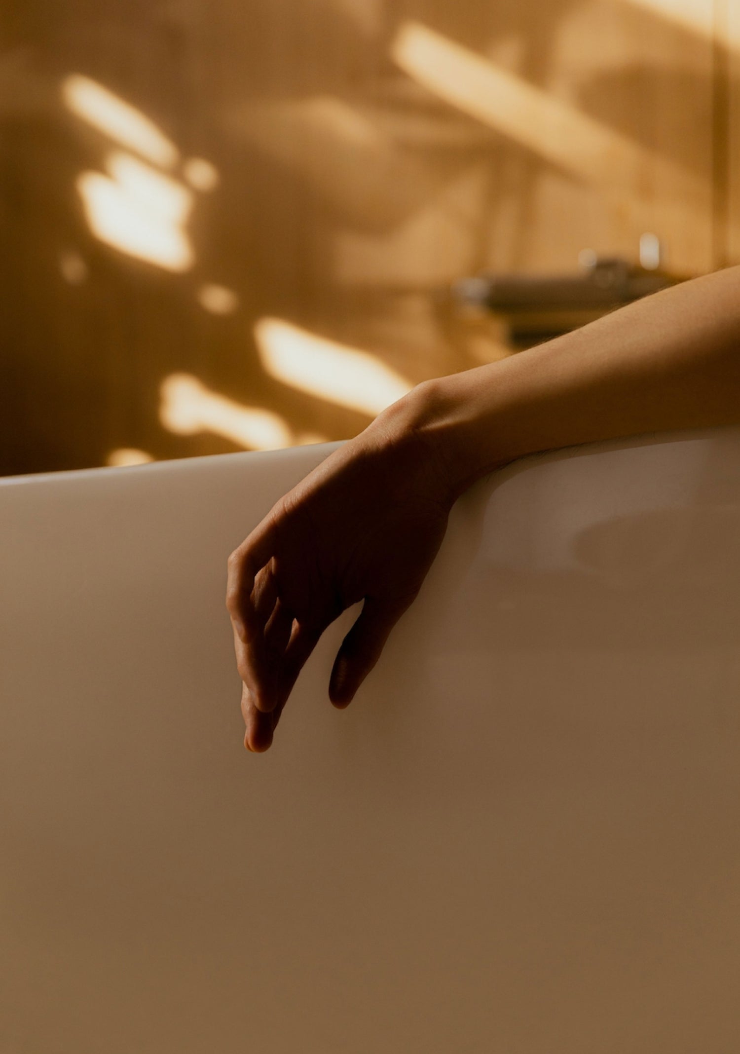A hand hanging out of a bubble bath tub